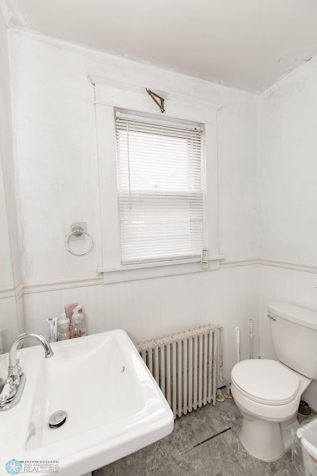 bathroom with radiator heating unit, toilet, sink, and tile patterned floors