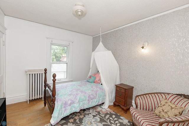 bedroom with a textured ceiling, light hardwood / wood-style flooring, and radiator