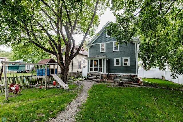 rear view of house featuring a yard and a playground