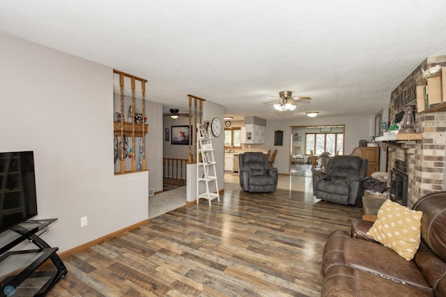 living room featuring a fireplace, ceiling fan, a textured ceiling, and hardwood / wood-style flooring