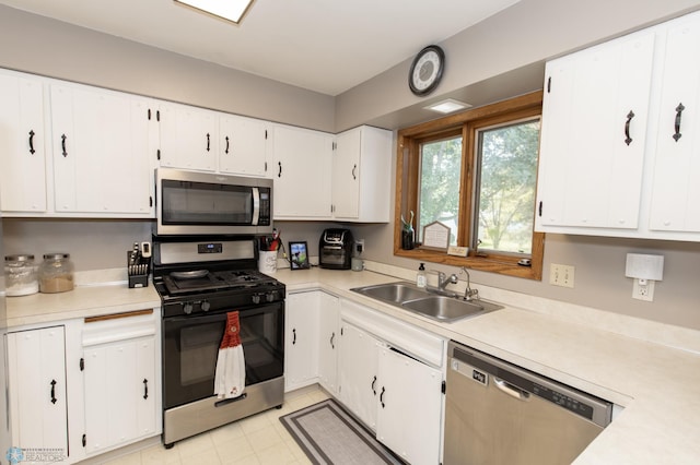 kitchen featuring appliances with stainless steel finishes, light tile patterned flooring, white cabinets, and sink