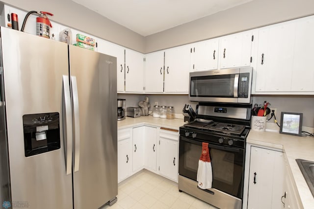 kitchen featuring light tile patterned floors, sink, stainless steel appliances, and white cabinets