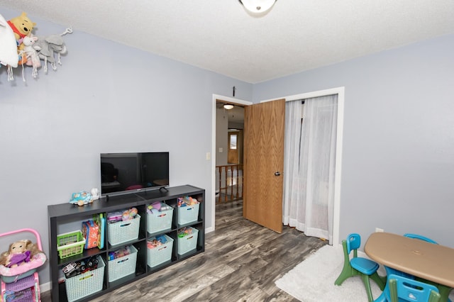 rec room featuring a textured ceiling and dark hardwood / wood-style flooring