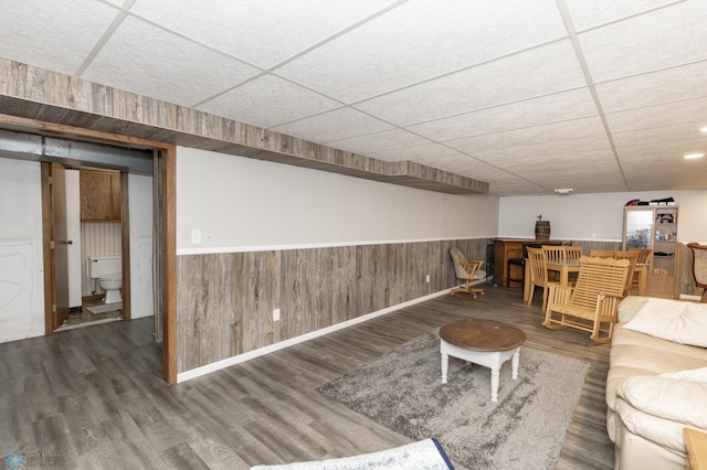 living room featuring dark wood-type flooring and a paneled ceiling