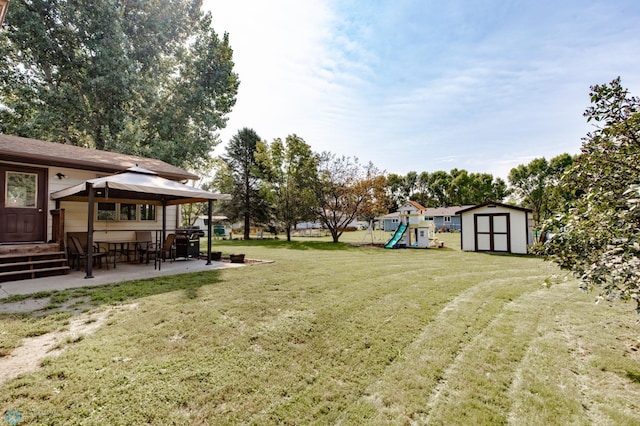 view of yard with a patio, a shed, and a playground