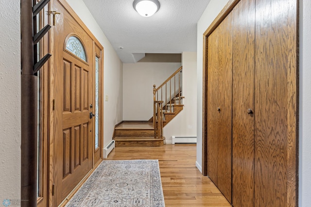 entrance foyer featuring a baseboard heating unit, a textured ceiling, and light wood-type flooring