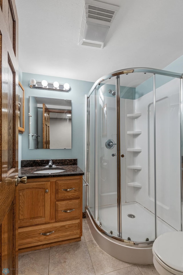 bathroom featuring vanity, a shower with shower door, toilet, and tile patterned floors