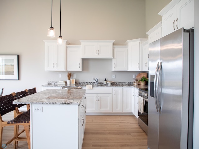 kitchen featuring appliances with stainless steel finishes, hanging light fixtures, a breakfast bar, light wood-type flooring, and a center island