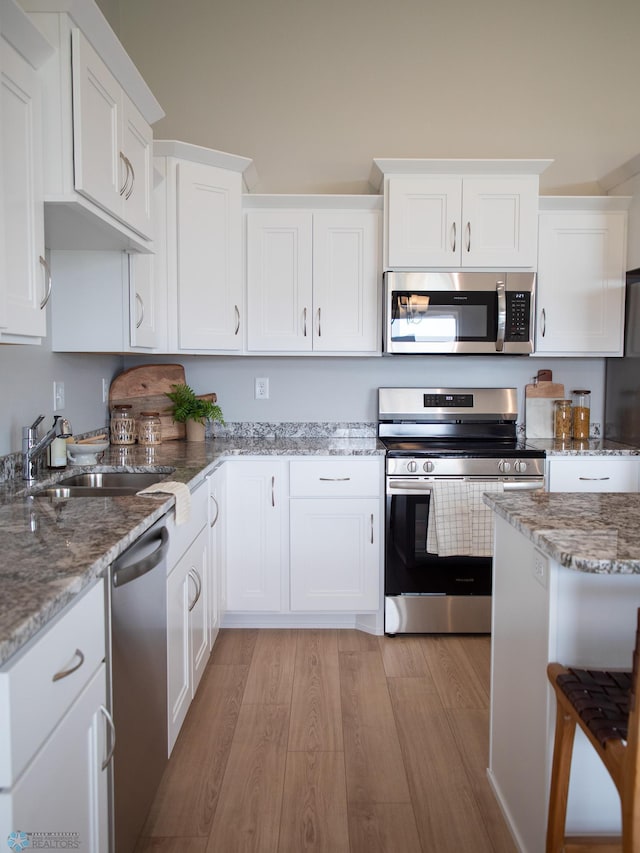 kitchen featuring sink, stainless steel appliances, light hardwood / wood-style floors, and white cabinetry