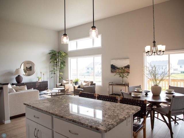 kitchen with a healthy amount of sunlight, light hardwood / wood-style floors, pendant lighting, and white cabinets