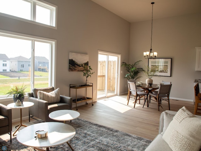 living room with light hardwood / wood-style flooring, a high ceiling, and a notable chandelier