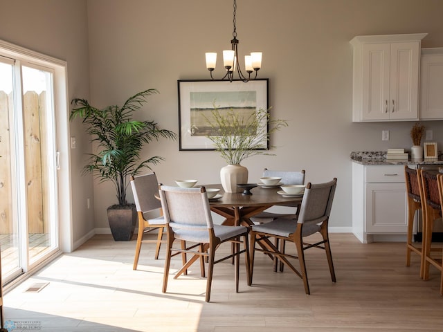 dining room with light hardwood / wood-style flooring and an inviting chandelier