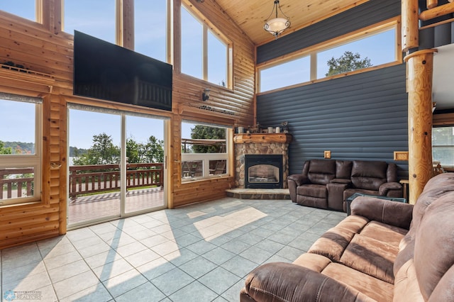 tiled living room with a stone fireplace, log walls, a high ceiling, and wood ceiling