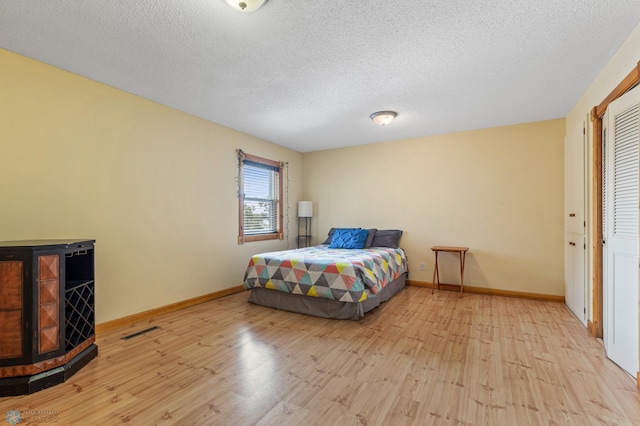 bedroom with a textured ceiling, a closet, and light wood-type flooring