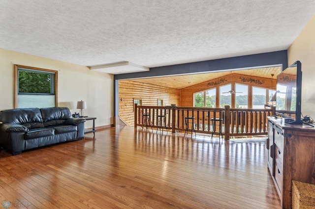 living room with hardwood / wood-style floors, vaulted ceiling with beams, and a textured ceiling