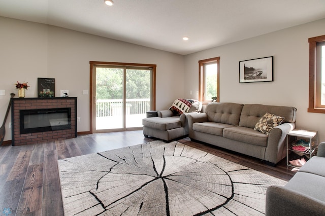 living room featuring vaulted ceiling, dark hardwood / wood-style floors, and a brick fireplace