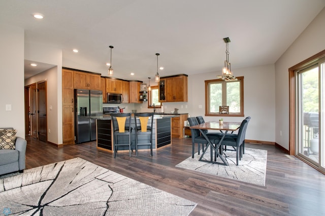 interior space with decorative light fixtures, appliances with stainless steel finishes, dark wood-type flooring, and a kitchen island