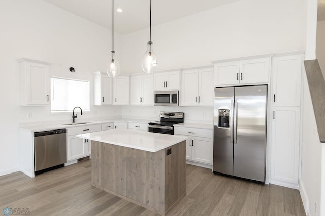 kitchen with a kitchen island, light hardwood / wood-style flooring, stainless steel appliances, sink, and white cabinets