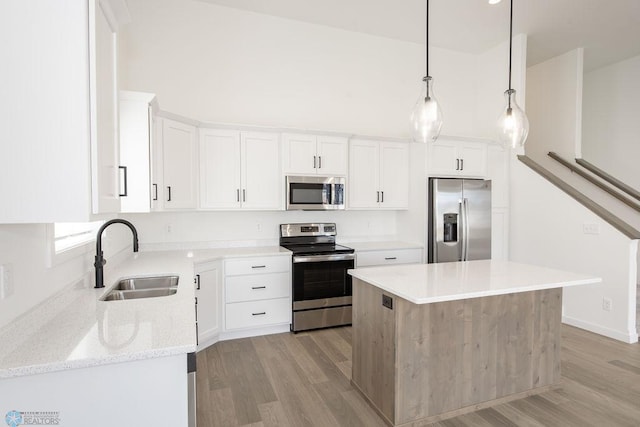 kitchen with white cabinets, appliances with stainless steel finishes, a center island, and sink