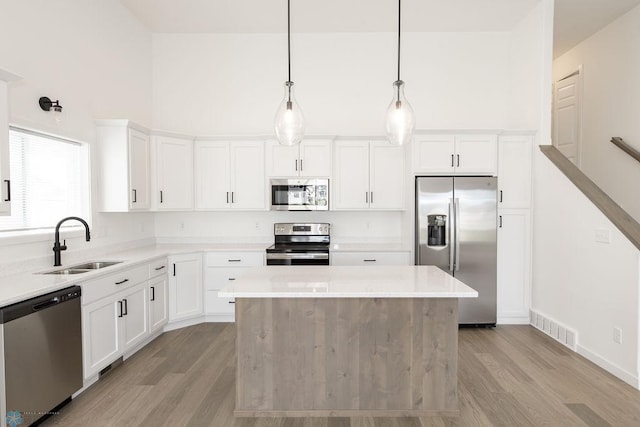 kitchen with a center island, stainless steel appliances, sink, and light hardwood / wood-style flooring