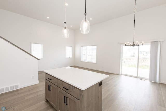 kitchen with pendant lighting, a high ceiling, and light wood-type flooring