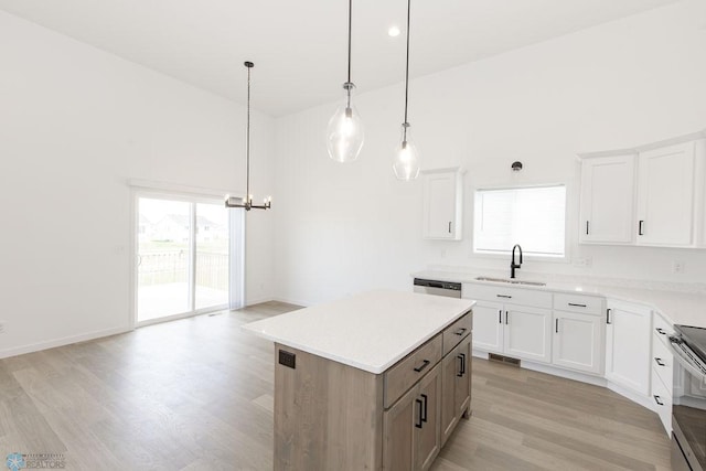 kitchen with decorative light fixtures, a kitchen island, sink, white cabinets, and light hardwood / wood-style floors