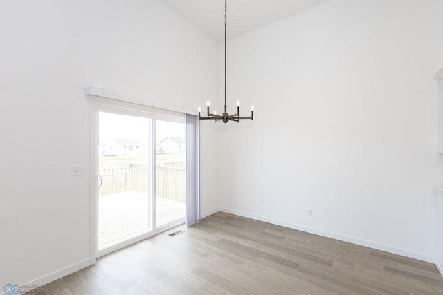 unfurnished dining area with light wood-type flooring and an inviting chandelier