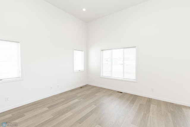 empty room featuring a high ceiling and light wood-type flooring