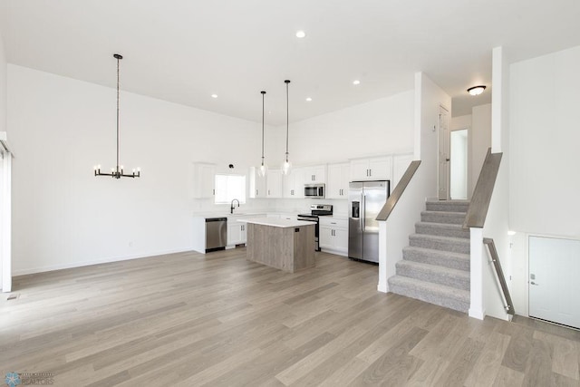 kitchen featuring a center island, stainless steel appliances, light hardwood / wood-style floors, and white cabinetry