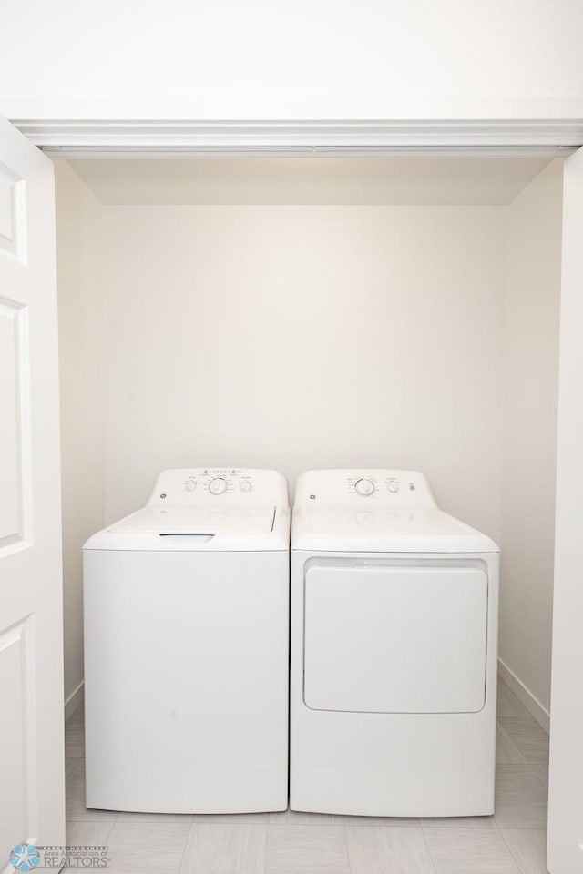 clothes washing area with light tile patterned floors and independent washer and dryer