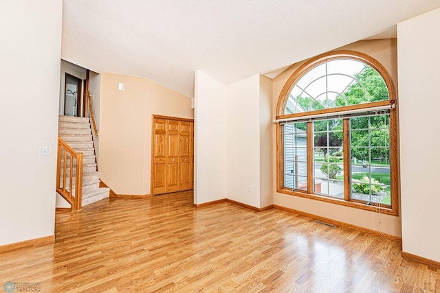 empty room featuring light wood-type flooring and lofted ceiling