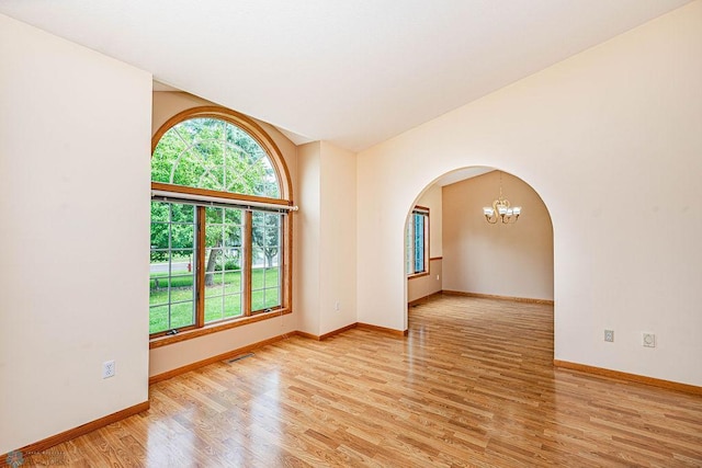 spare room with light wood-type flooring and a notable chandelier