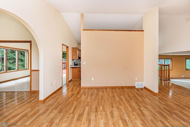 unfurnished living room featuring high vaulted ceiling and light hardwood / wood-style floors