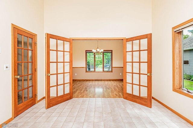 unfurnished room featuring a chandelier, light hardwood / wood-style floors, and french doors