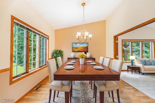 dining space with lofted ceiling, plenty of natural light, a chandelier, and light hardwood / wood-style floors