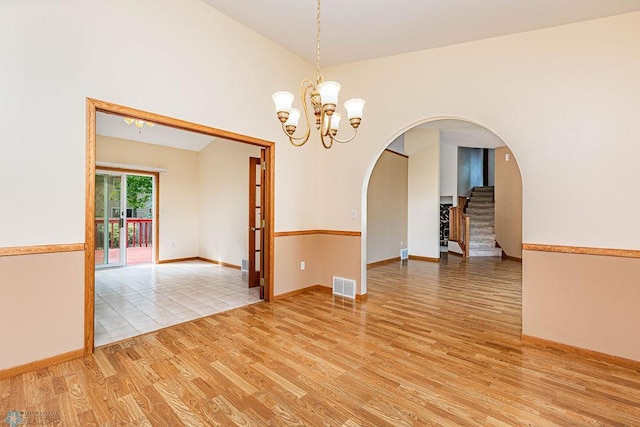 unfurnished room featuring a chandelier and light hardwood / wood-style floors