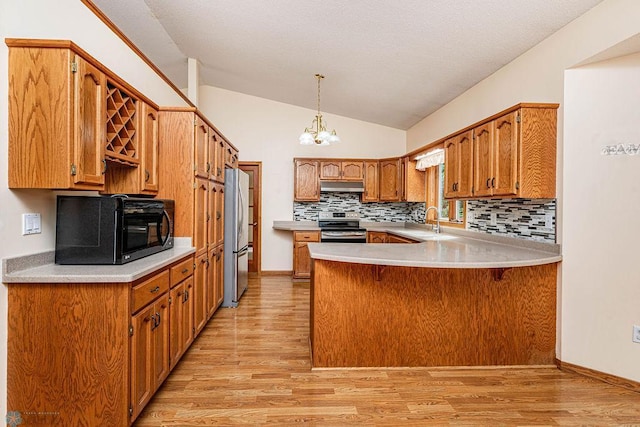 kitchen with light hardwood / wood-style flooring, appliances with stainless steel finishes, a notable chandelier, kitchen peninsula, and pendant lighting