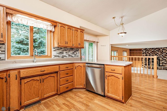 kitchen with pendant lighting, light hardwood / wood-style flooring, stainless steel dishwasher, sink, and lofted ceiling