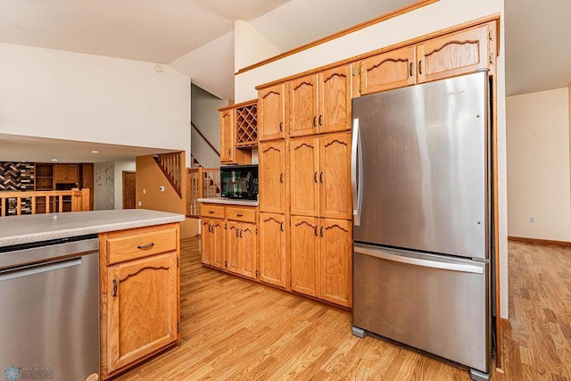 kitchen featuring light wood-type flooring, stainless steel appliances, and vaulted ceiling