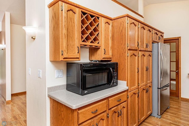 kitchen featuring stainless steel fridge, lofted ceiling, and light hardwood / wood-style floors