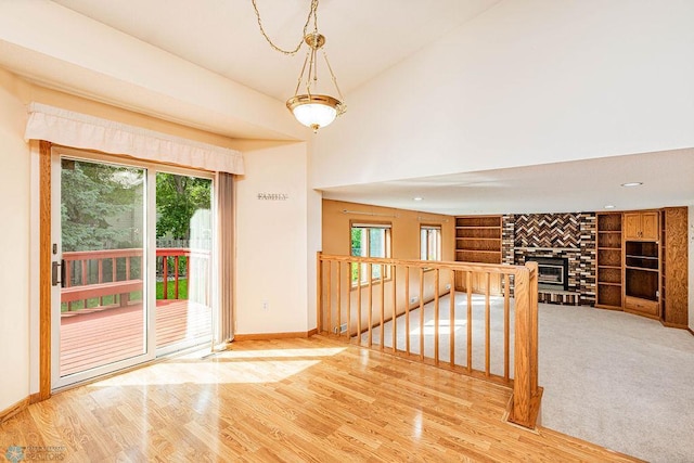 empty room with light hardwood / wood-style floors, a brick fireplace, and a wealth of natural light