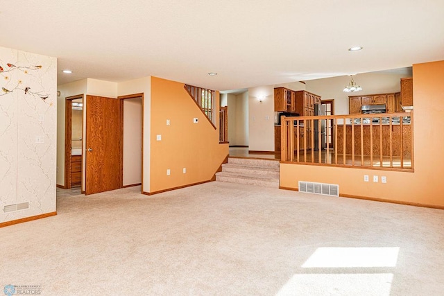 spare room featuring light carpet and an inviting chandelier