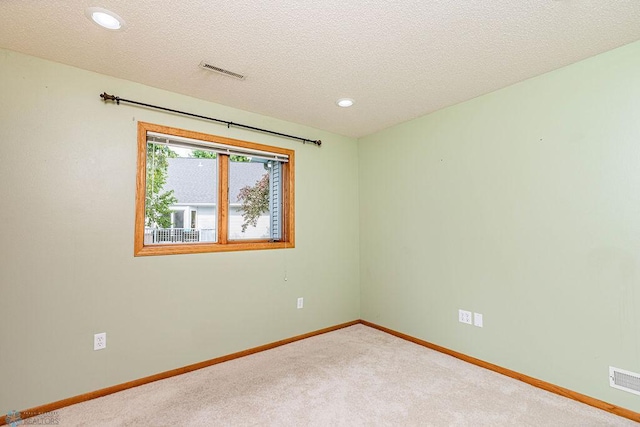 spare room featuring a textured ceiling and carpet