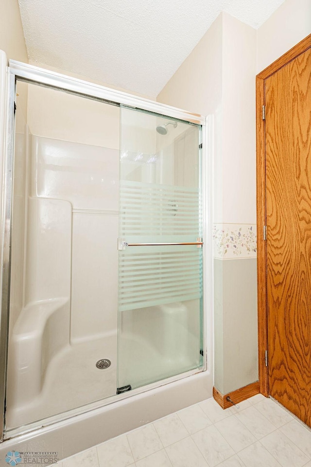 bathroom with tile patterned floors, a textured ceiling, and a shower with shower door