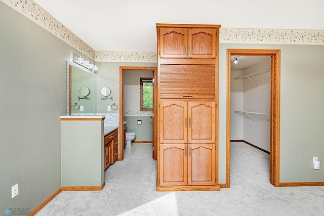 carpeted bedroom with a walk in closet, ensuite bathroom, and a closet