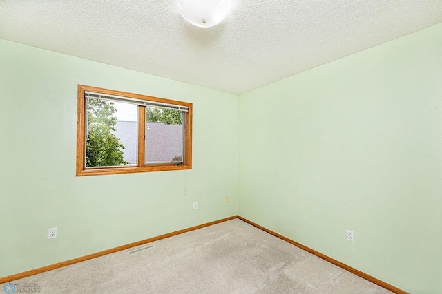 carpeted spare room with a textured ceiling