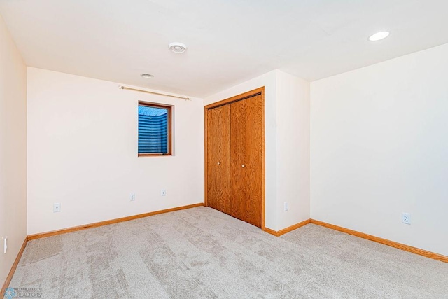 unfurnished bedroom featuring light colored carpet and a closet