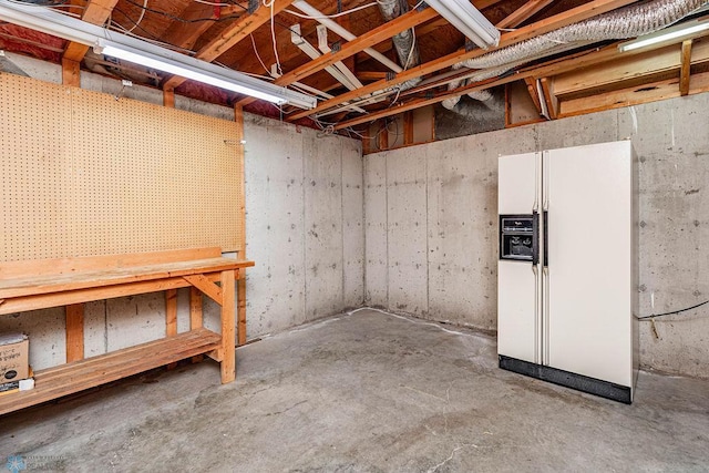 basement featuring white refrigerator with ice dispenser