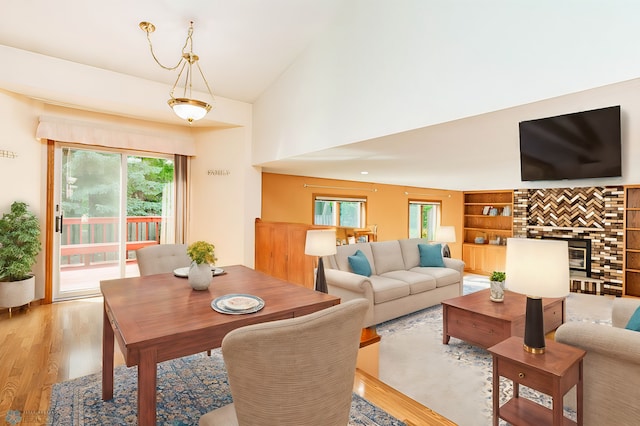 living room featuring light wood-type flooring, built in shelves, and vaulted ceiling