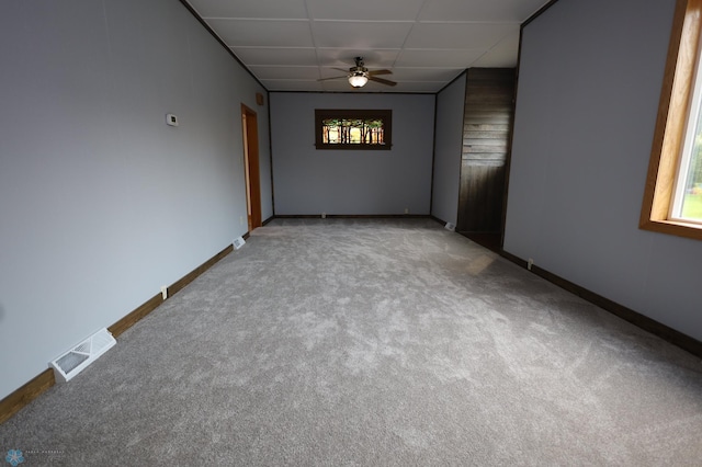 carpeted spare room with a paneled ceiling, a healthy amount of sunlight, and ceiling fan